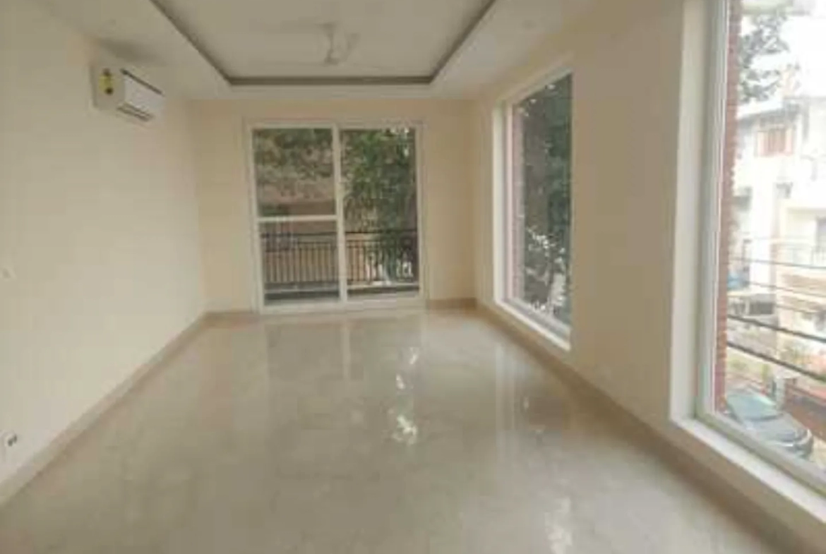 Spacious, bright room with polished floors, balcony access, large window, and tray ceiling in a Greater Kailash-1 rental apartment