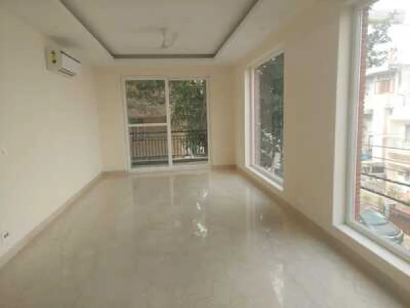 Spacious, bright room with polished floors, balcony access, large window, and tray ceiling in a Greater Kailash-1 rental apartment