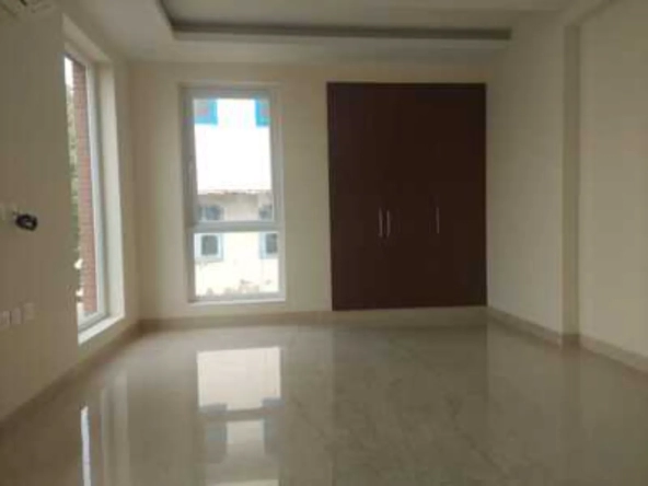 Interior shot of a room with polished flooring, two windows, and a dark wood wardrobe, rental in Greater Kailash-1.