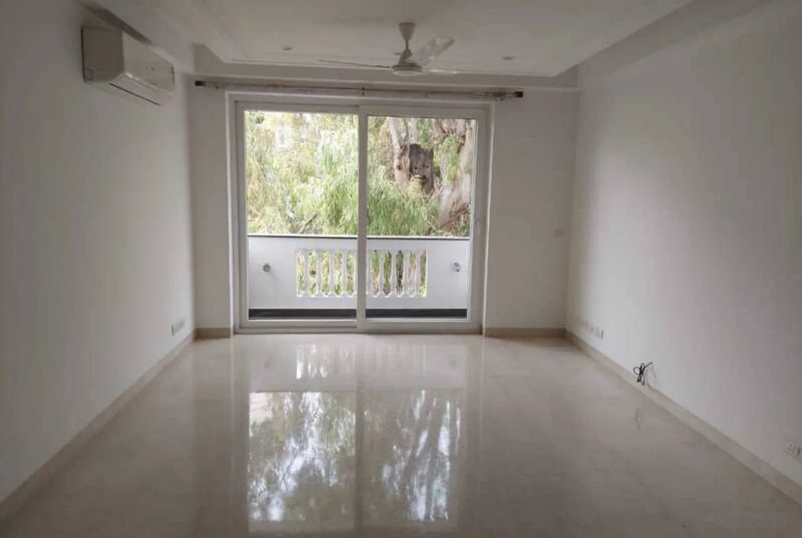 "Spacious, newly renovated apartment room with polished floors and balcony, view of trees, South Delhi rental."