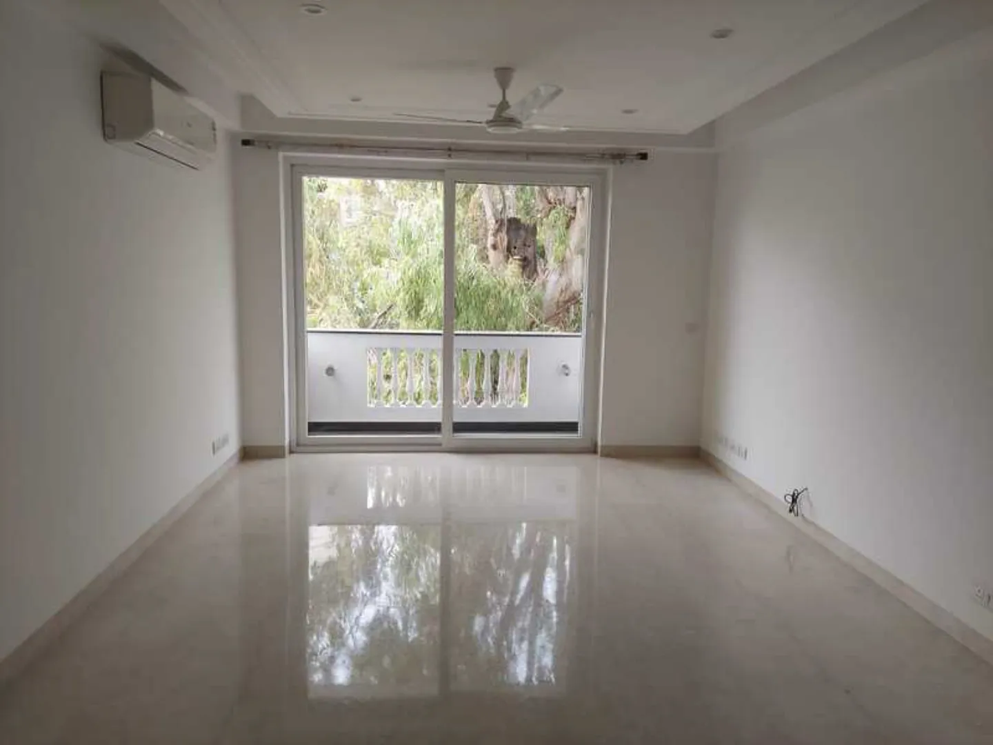 "Spacious, newly renovated apartment room with polished floors and balcony, view of trees, South Delhi rental."