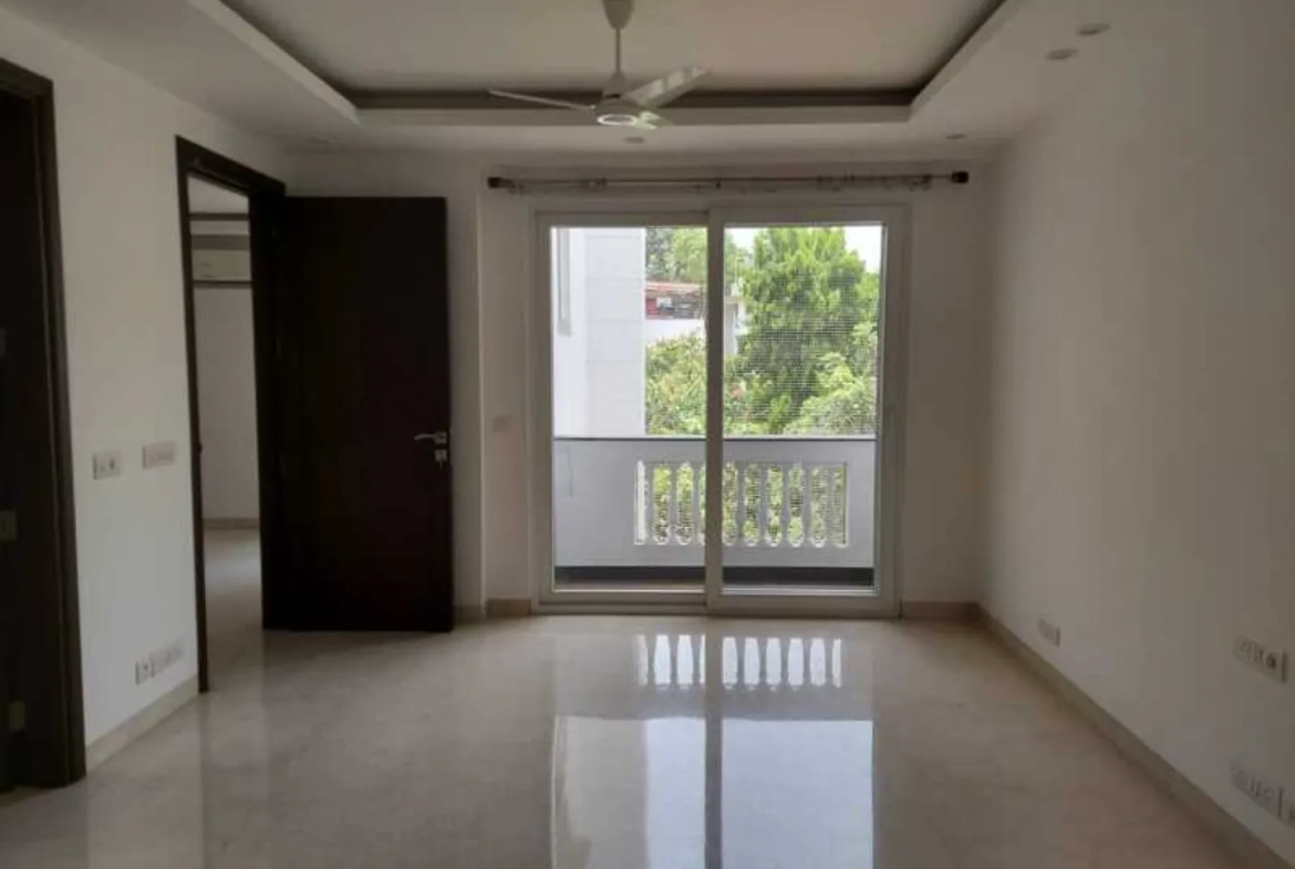 "Spacious apartment room with balcony and greenery view, South Delhi rental."