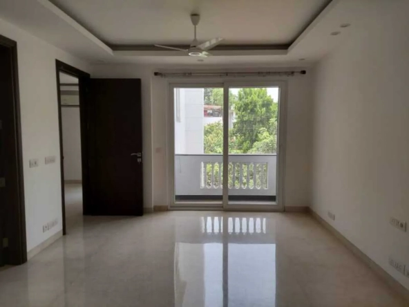 "Spacious apartment room with balcony and greenery view, South Delhi rental."