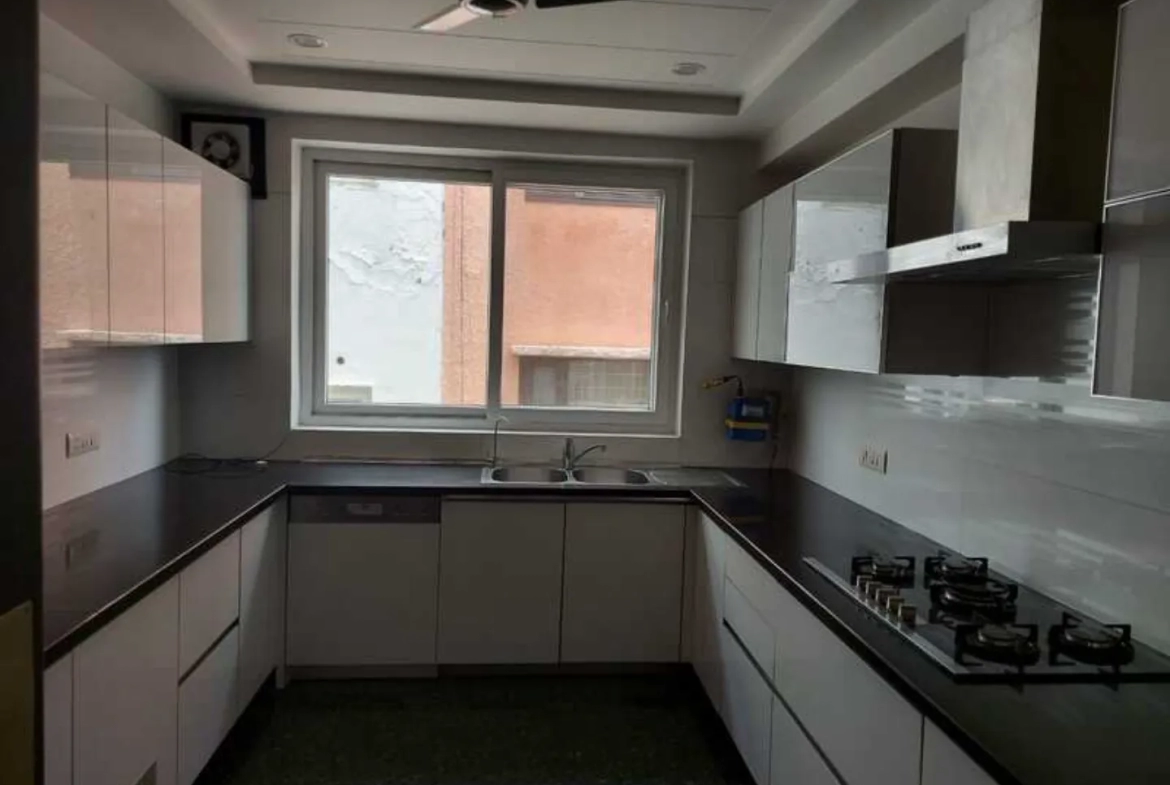 "Sleek kitchen with modular cabinets, gas stove, and dark countertops, South Delhi rental."