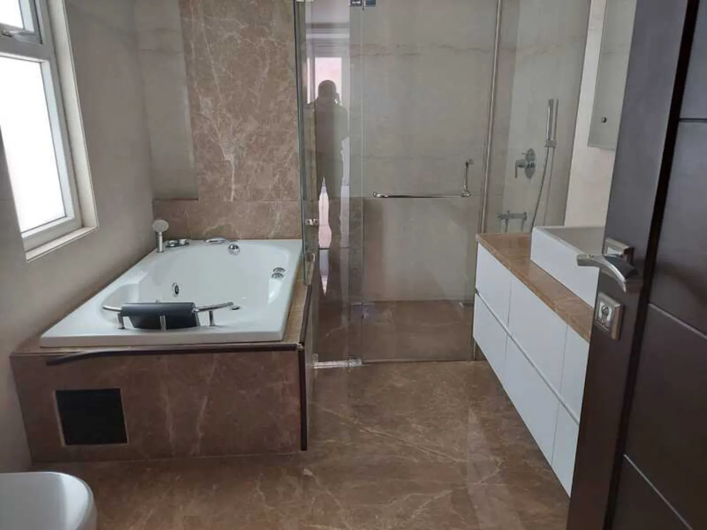 "Bathroom with bathtub, glass shower, and vanity, modern design, South Delhi rental."