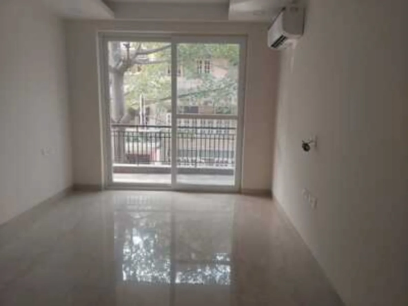 Empty room with sliding glass doors to a balcony, polished floor tiles, and AC unit in a rental apartment in Greater Kailash-1, South Delhi.